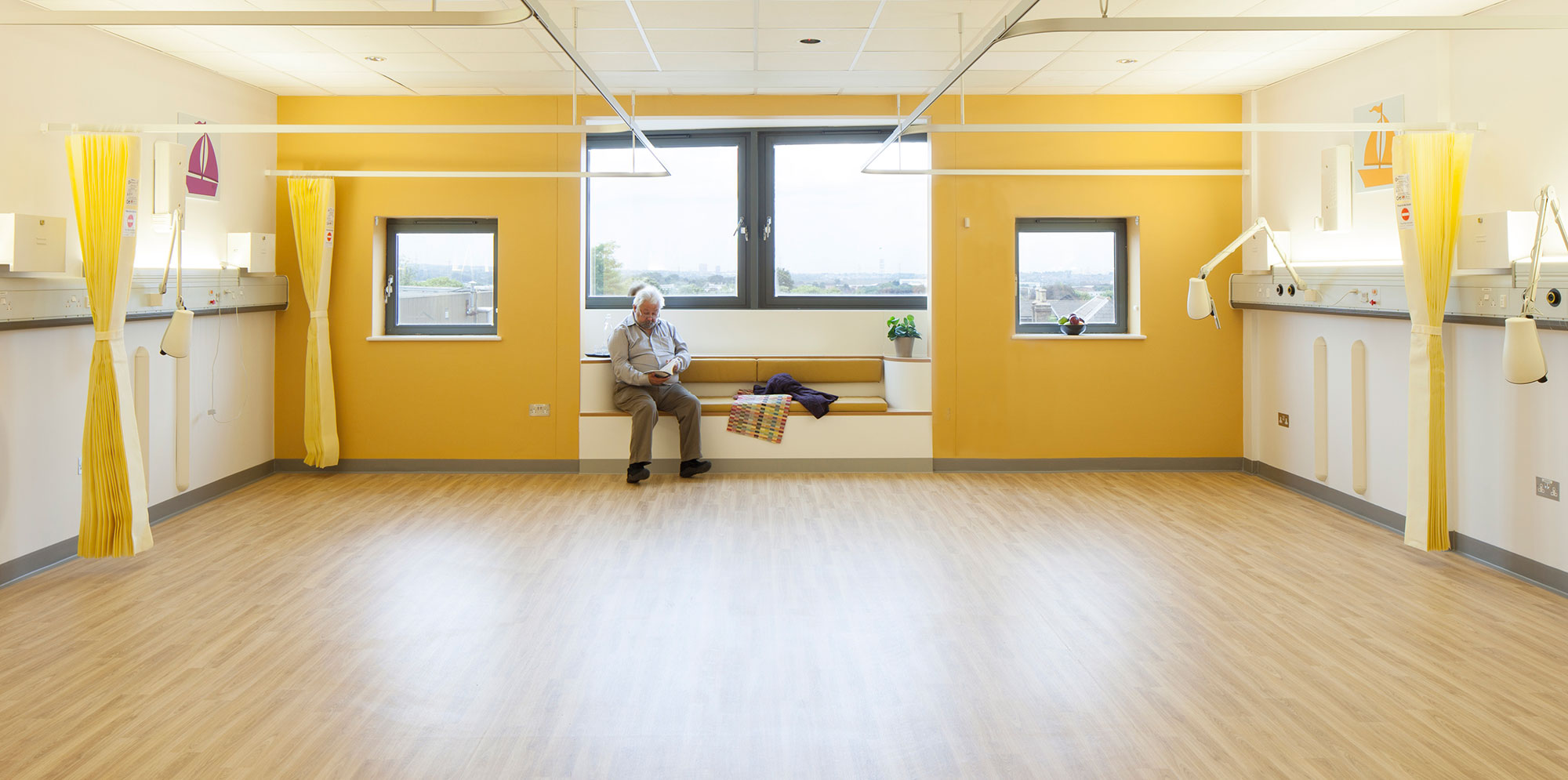 Empty patient room with yellow walls and curtains inside Croydon University hospital